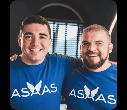Piero e Diego, os fundadores do Asaas, abraçados e sorrindo. Estão vestindo a camiseta com o logotipo da empresa.